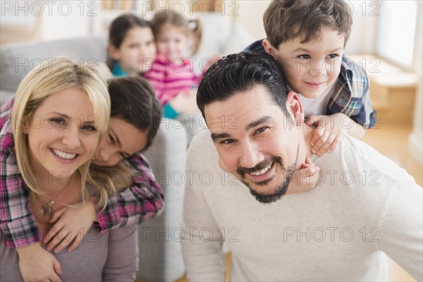 Caucasian parents carrying children piggyback in living room