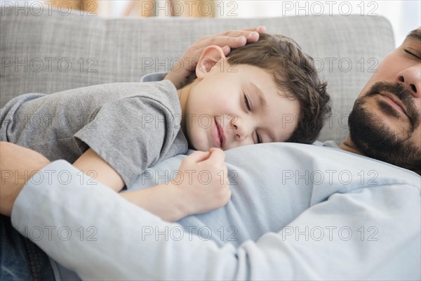 Caucasian father and son napping on sofa