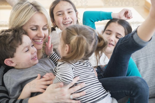 Caucasian mother and children playing on sofa