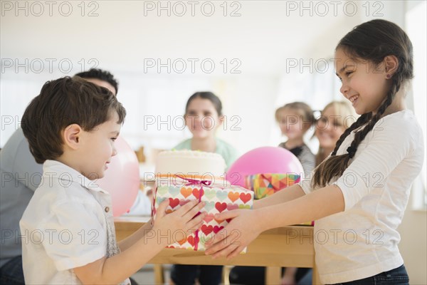 Caucasian girl giving brother birthday gift at party