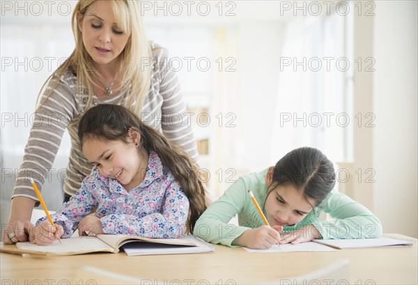 Caucasian mother helping daughters do homework