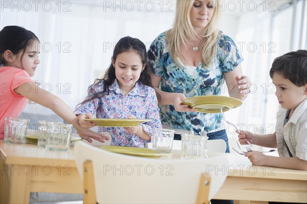 Caucasian mother and children setting table