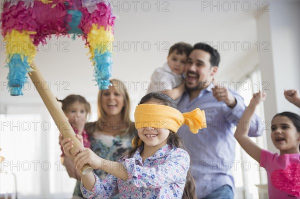 Caucasian girl hitting pinata at birthday party