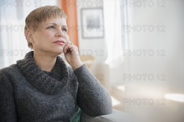 Anxious Caucasian woman sitting on sofa