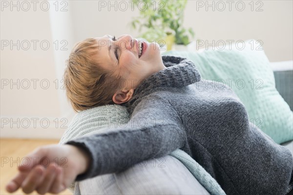 Laughing Caucasian woman laying on sofa