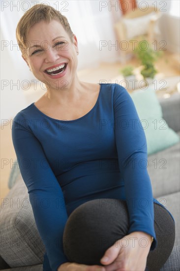 Laughing Caucasian woman sitting on sofa