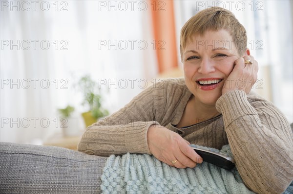 Caucasian woman holding remote control on sofa
