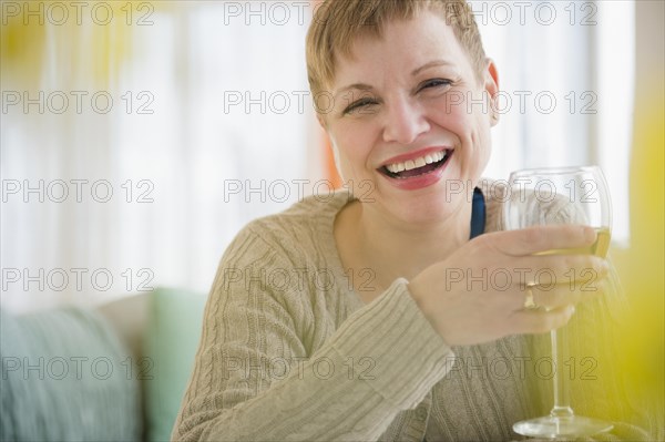 Caucasian woman drinking glass of wine on sofa