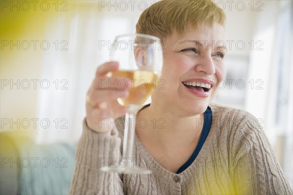 Caucasian woman drinking glass of wine in living room