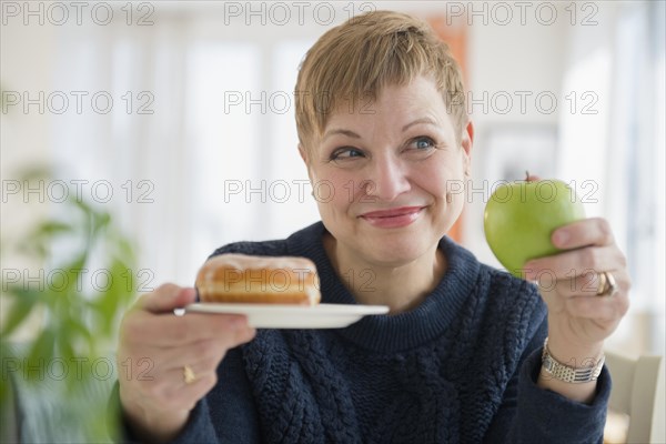 Caucasian woman choosing between donut and apple