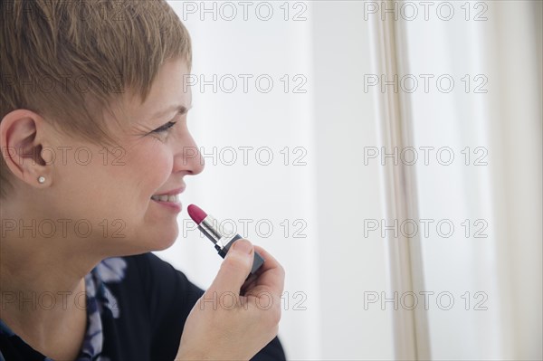 Caucasian woman applying lipstick