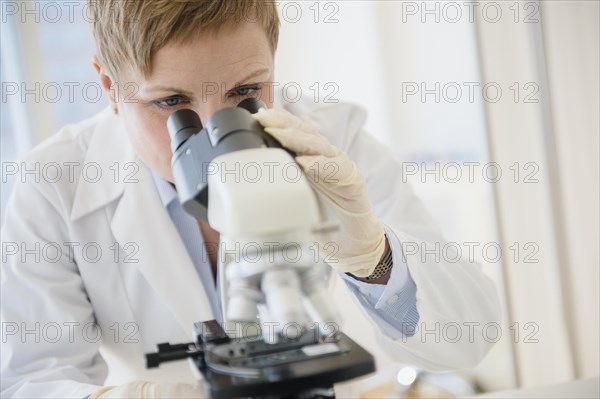 Caucasian scientist looking through microscope in lab