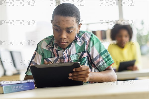 Black student using digital tablet in classroom