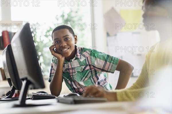 Black student smiling near computers in classroom