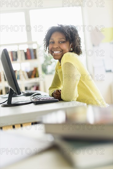 Black student smiling at computer in classroom