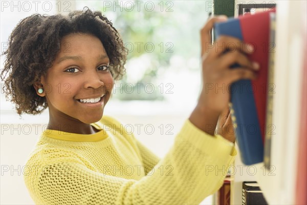 Black student choosing book from library shelf