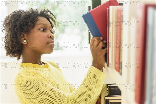 Black student choosing book from library shelf