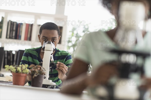 Black students using microscopes in science lab