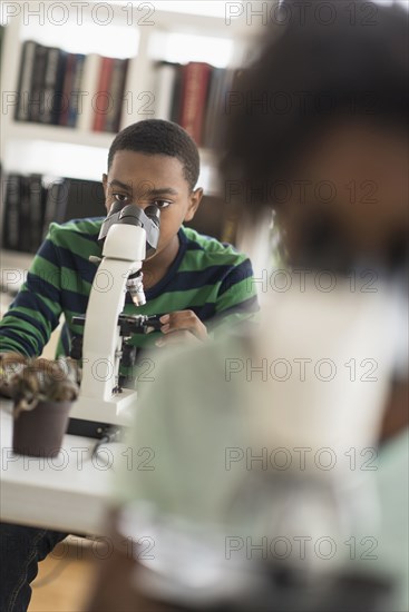 Black students using microscopes in science lab