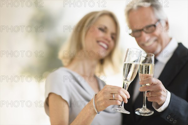Smiling older Caucasian couple toasting with champagne