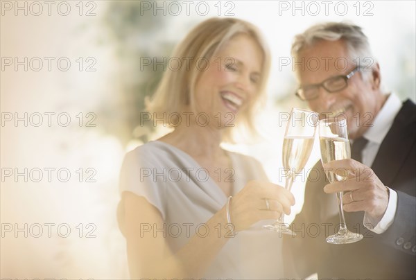 Smiling older Caucasian couple toasting with champagne