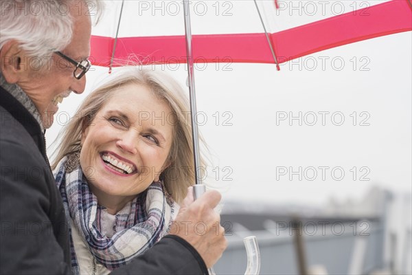 Older Caucasian couple standing under umbrella