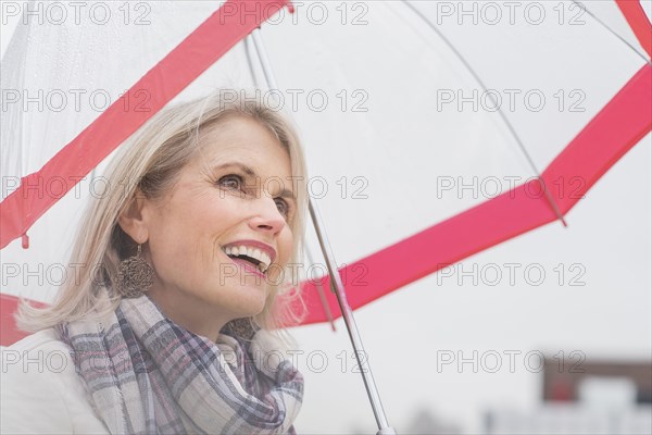 Older Caucasian woman standing under umbrella