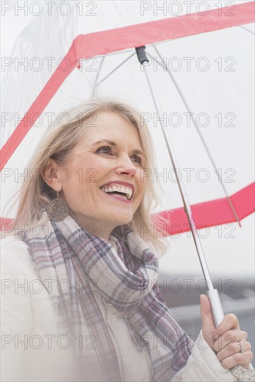 Older Caucasian woman standing under umbrella