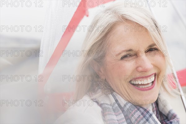 Older Caucasian woman standing under umbrella