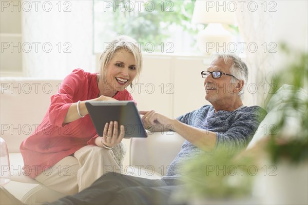Older Caucasian couple using digital tablet in living room