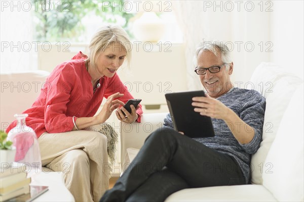 Older Caucasian couple using technology in living room