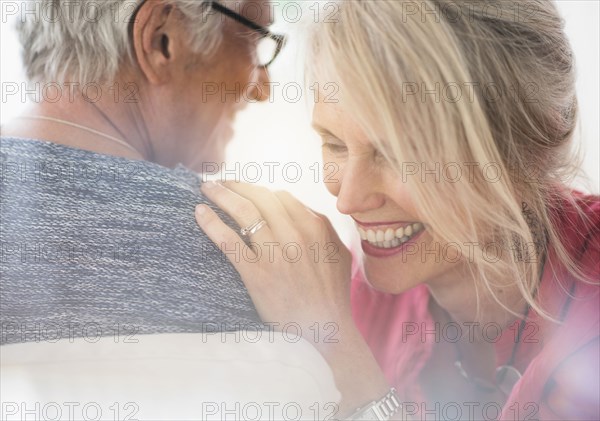 Close up of older Caucasian couple whispering