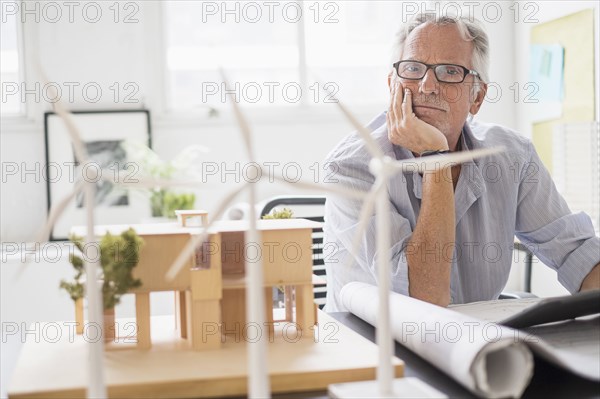 Older Caucasian architect examining scale model in office