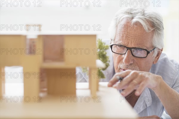 Older Caucasian architect building scale model in office