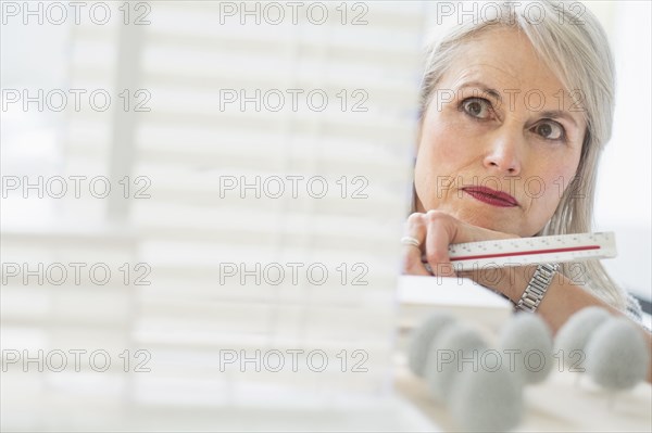 Older Caucasian architect examining scale model in office