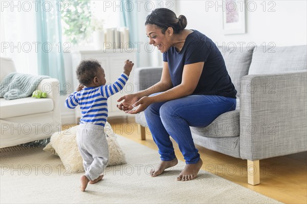 Mixed race mother playing with baby son in living room