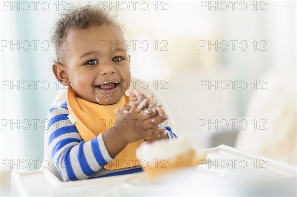 Mixed race baby boy eating in high chair