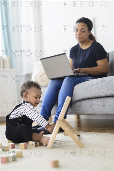 Mixed race mother and baby son relaxing in living room