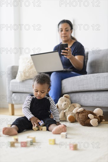 Mixed race mother and baby son relaxing in living room