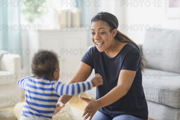 Mixed race mother playing with baby son in living room