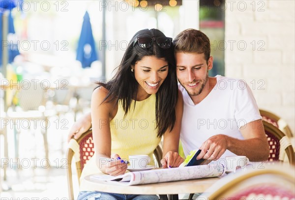 Hispanic couple reading map at cafe