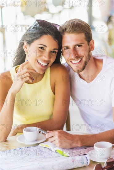 Hispanic couple reading map at cafe