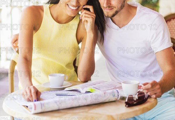 Hispanic couple reading map at cafe