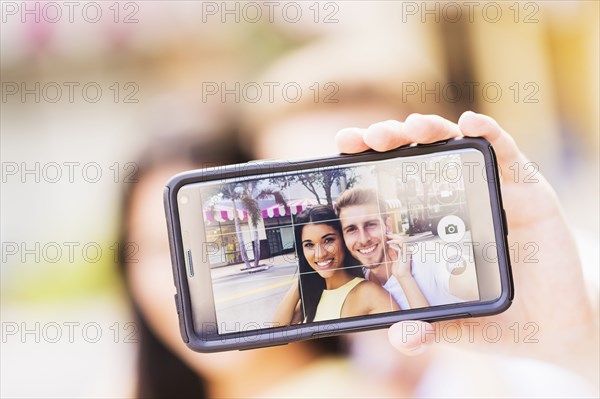 Close up of Hispanic couple taking selfie outdoors