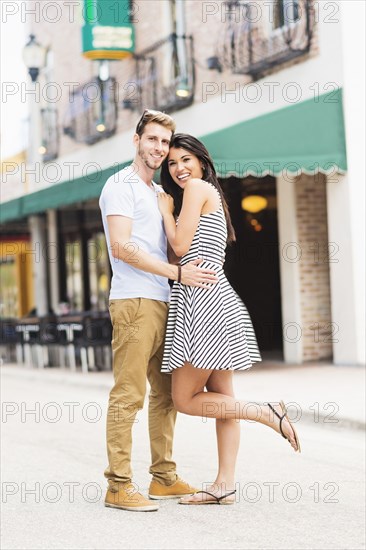 Hispanic couple hugging on sidewalk