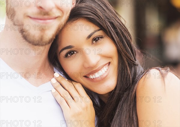 Hispanic woman hugging boyfriend on sidewalk