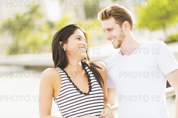 Hispanic couple hugging on bridge over urban river