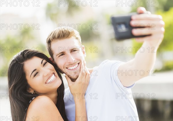 Hispanic couple taking selfie outdoors