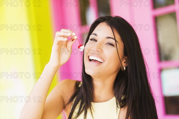 Hispanic woman eating cherry outdoors