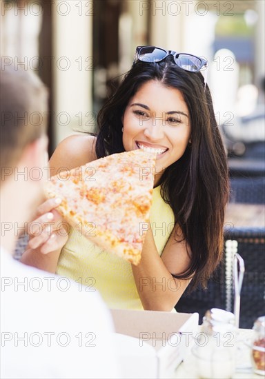 Hispanic couple eating pizza at cafe